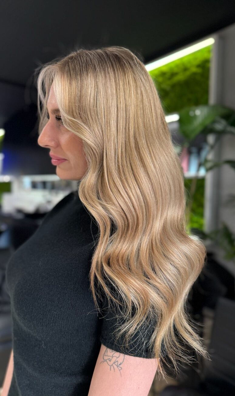 Długie falowane włosy w jasnym balejażu, ujęcie z boku